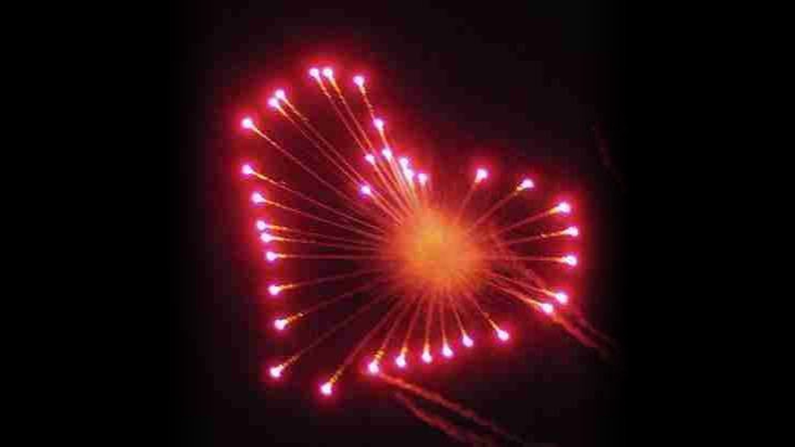 A red heart-shaped firework shell against a black sky.